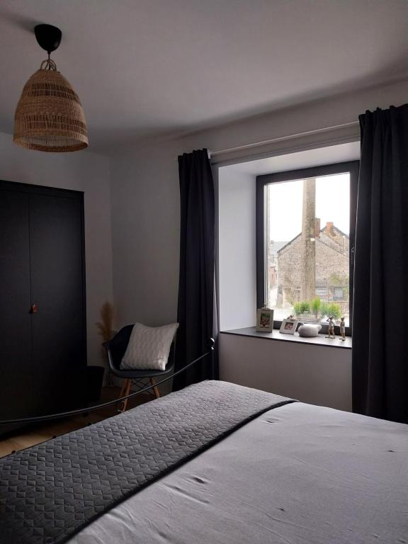 库万Au Cœur des Vallées的一间卧室配有一张床和一个带椅子的窗户