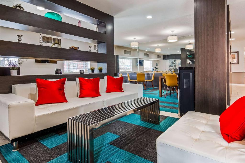休斯顿Baymont by Wyndham Houston/Westchase的客厅配有2张白色沙发和红色枕头
