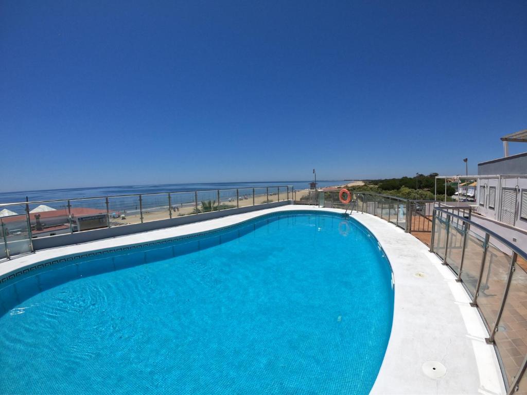 伊斯兰蒂拉islantilla vistas al mar 1 linea, piscina, parking, wifi的一座背景海洋的游泳池