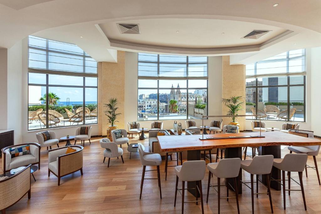 圣朱利安斯Malta Marriott Resort & Spa的餐厅设有桌椅和大窗户。