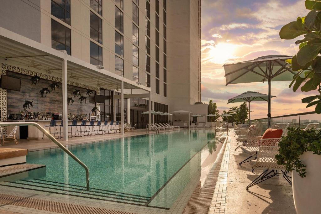 劳德代尔堡The Dalmar, Fort Lauderdale, a Tribute Portfolio Hotel的游泳池,酒店配有椅子和遮阳伞