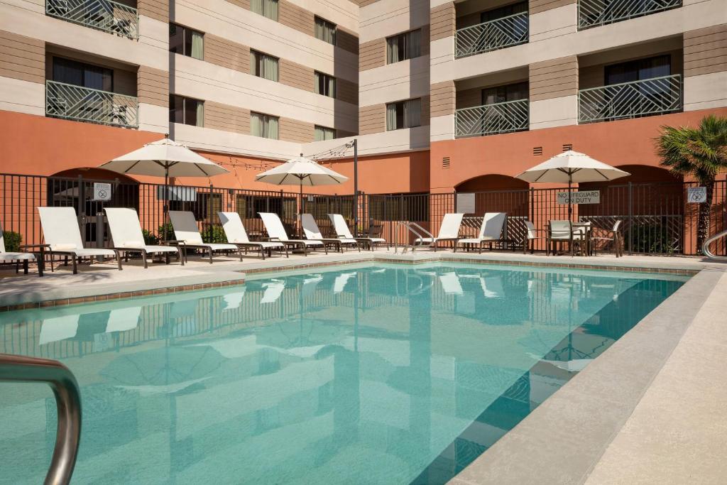 斯科茨Courtyard by Marriott Scottsdale Old Town的酒店前的游泳池配有椅子和遮阳伞