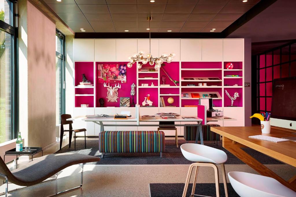 奥伯丁慕尼黑机场慕奇夕酒店的用餐室设有粉红色的墙壁和桌椅