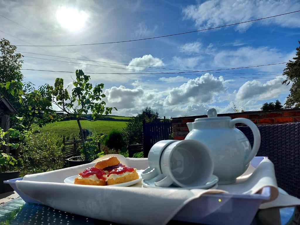ChallacombeLongstone Luxury Country Boutique Two Bedroom Cottage, Exmoor, Challacombe, North Devon的桌上放着食物和茶壶的盘子