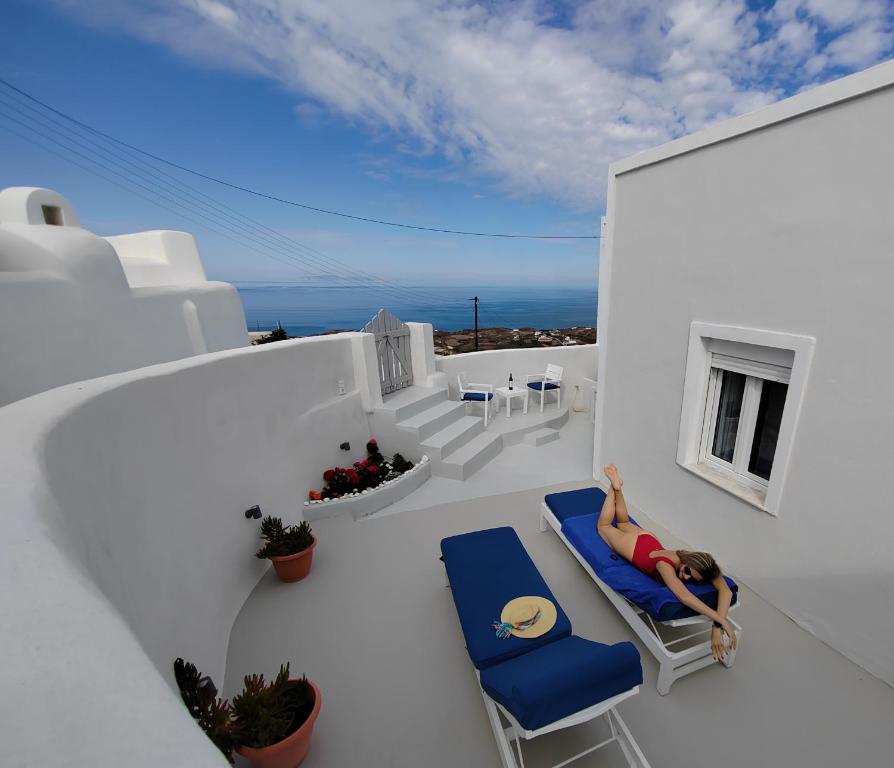 VourvoúlosWhite Swallow Suite Santorini的躺在房子阳台上的椅子上的女人