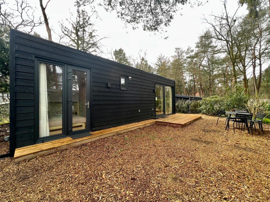 宁斯佩特Ultiem ontspannen in compleet ingericht tiny house in bosrijke omgeving的坐在院子顶上的一间黑色小房子