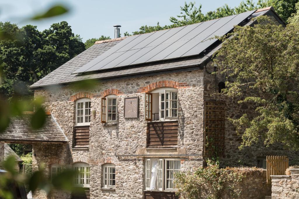 索尔塔什Lower Marsh Farm in Cornwall的一座古老的石头房子,屋顶上设有太阳能电池板