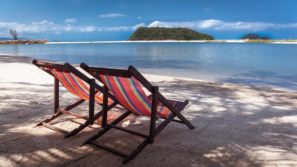 通萨拉班蒙拉里度假酒店的坐在海滩上靠近水面的摇椅