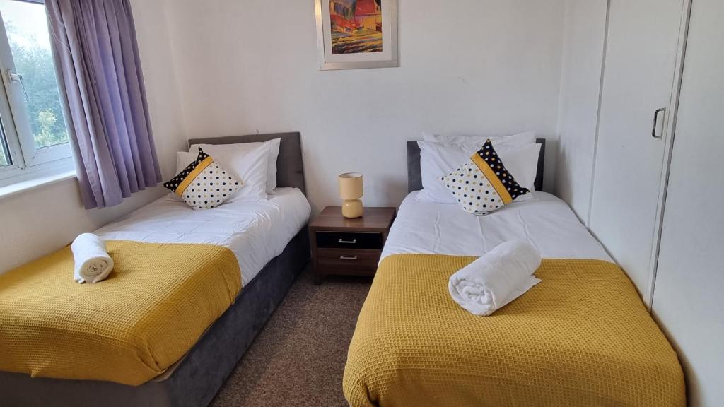 巴塞尔顿RTM COMFORTABLE Home的一间卧室配有两张带黄白色床单的床