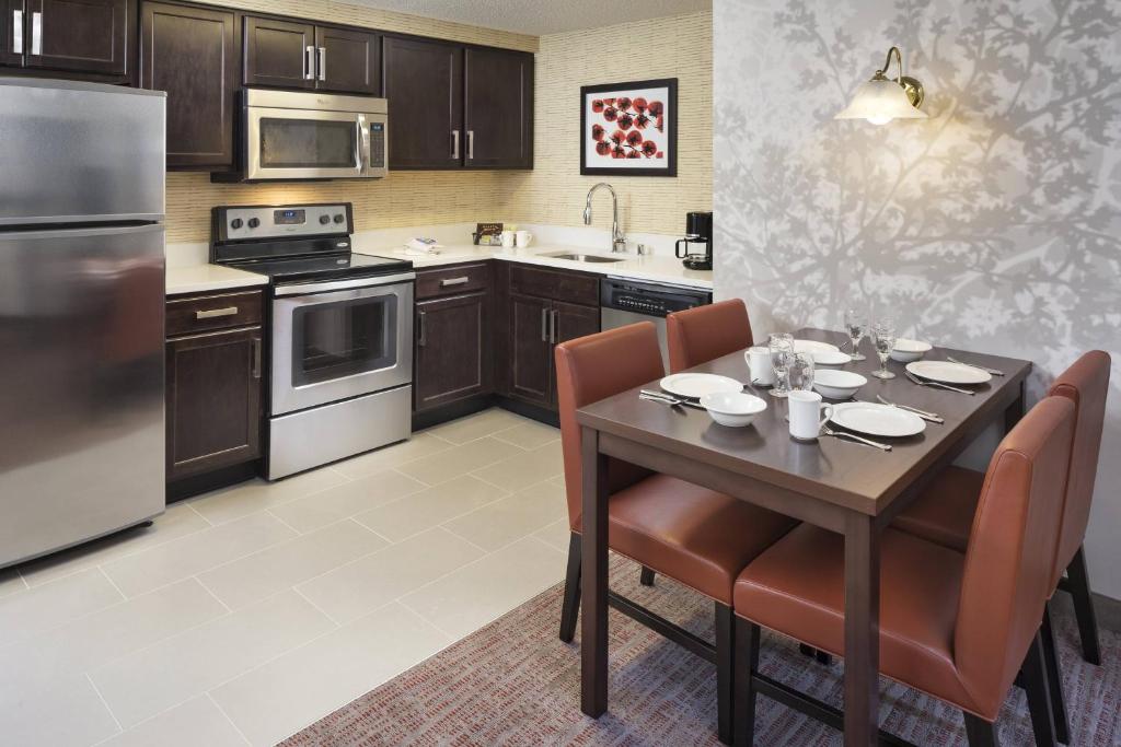 明尼阿波利斯明尼阿波利斯市中心旅行者酒店的带桌椅的厨房以及带不锈钢用具的厨房。