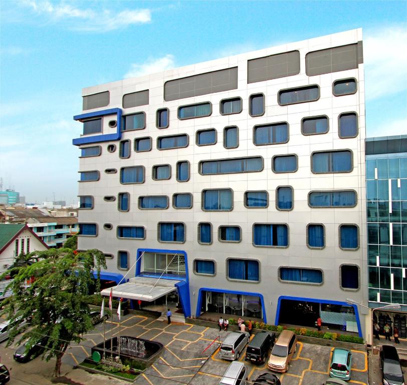 棉兰卡利比亚精品酒店的一座白色的大建筑,设有蓝色的窗户和停车场