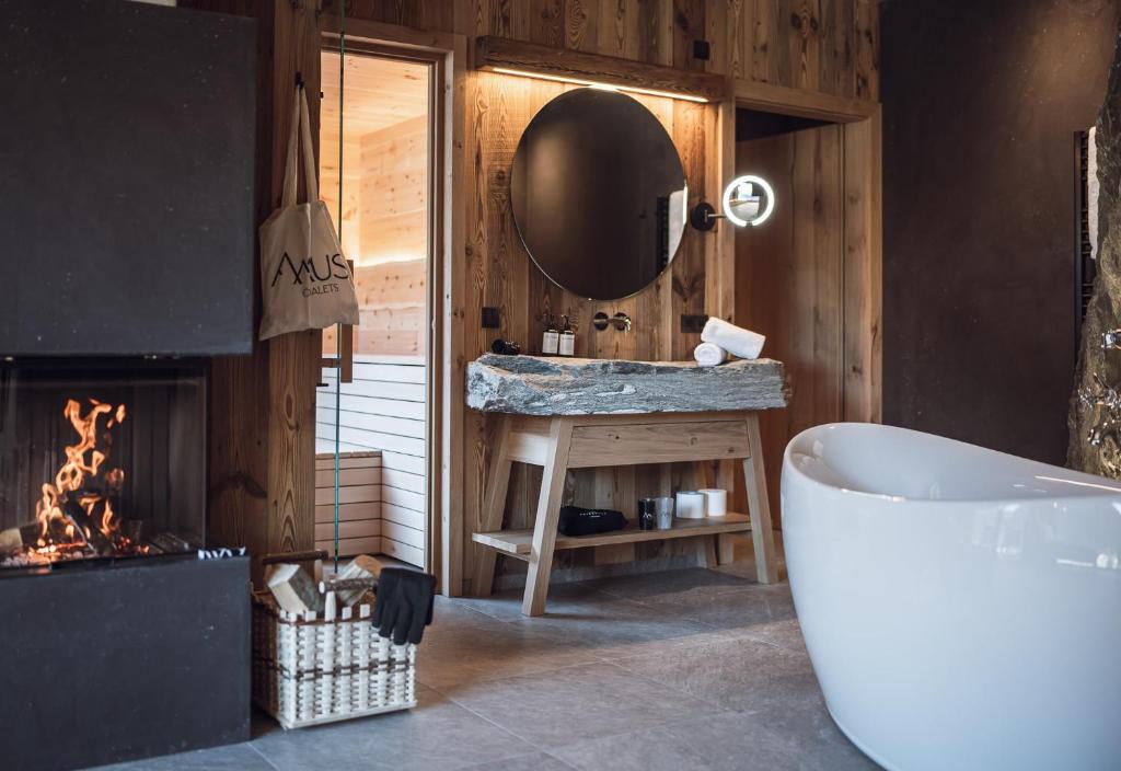 安泰塞尔瓦·迪·梅佐Amus Chalets Dolomites - Luxury Chalets South Tyrol的带浴缸、镜子和壁炉的浴室