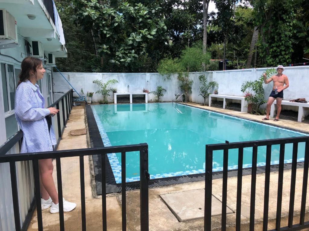 卡特勒格默Thisara Pool Resort Kataragama & Yala & Kabiliththa Safari的站在游泳池旁围栏上的女人