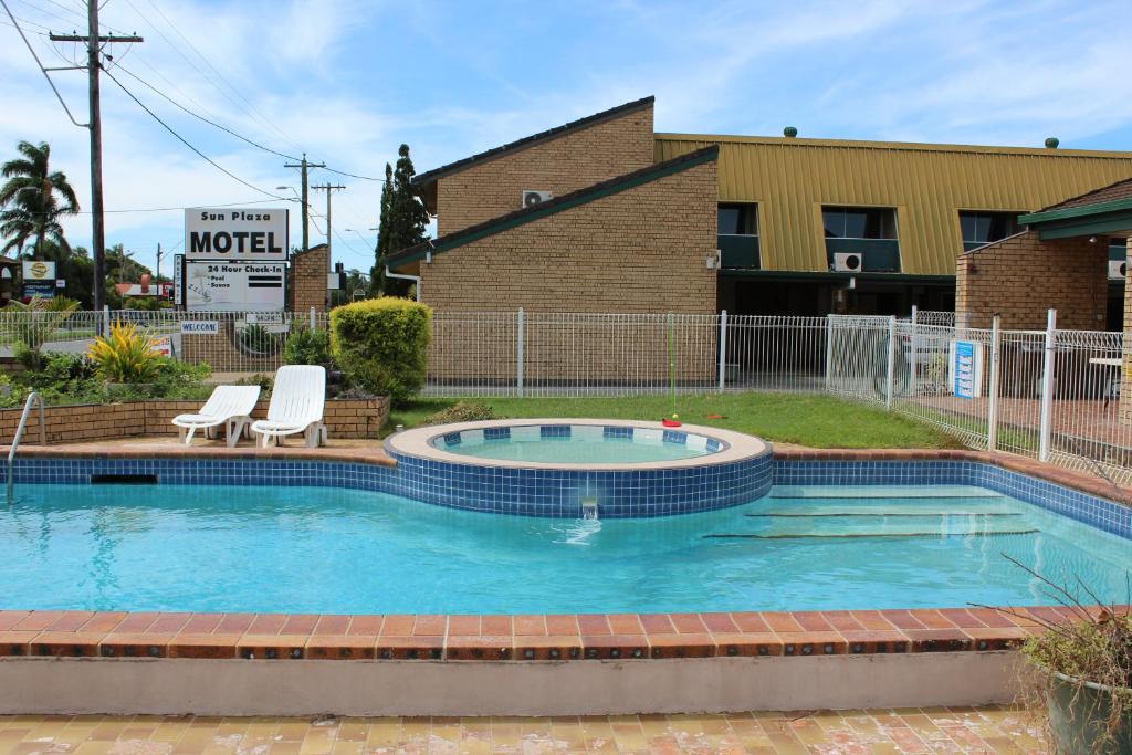 麦凯Sun Plaza Motel - Mackay的一座带两把椅子的游泳池以及一座建筑