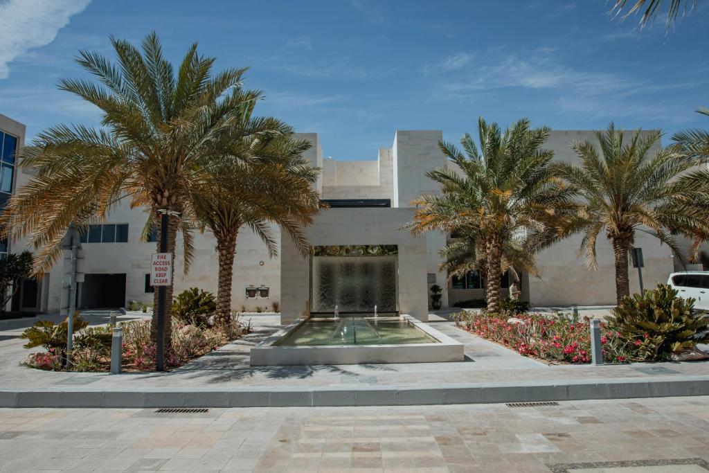 艾恩Alberni Jabal Hafeet Hotel Al Ain的喷泉前有棕榈树的建筑