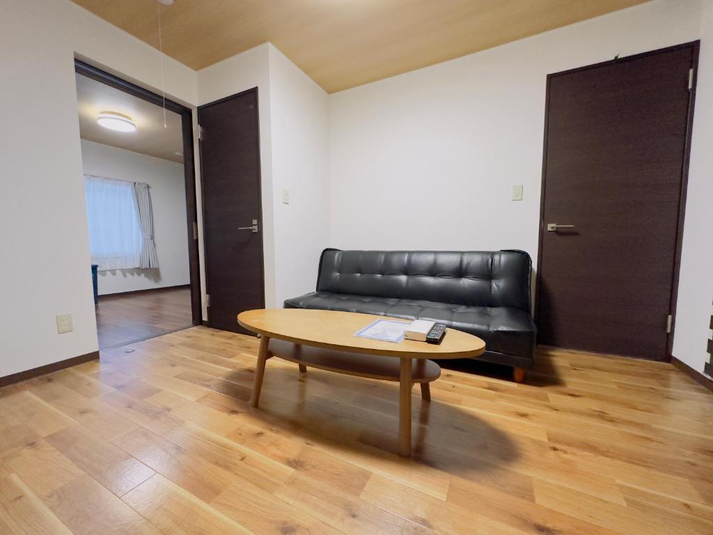 札幌リノベーション済み室内新築　Service Apartment Sapporoザ・ハウス4LDK86㎡的客厅配有黑色真皮沙发和桌子