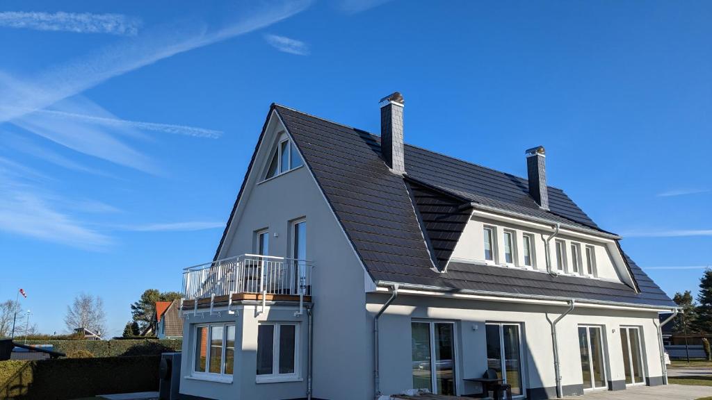 BresewitzFerienhaus Zur Oie的黑色屋顶的白色房子
