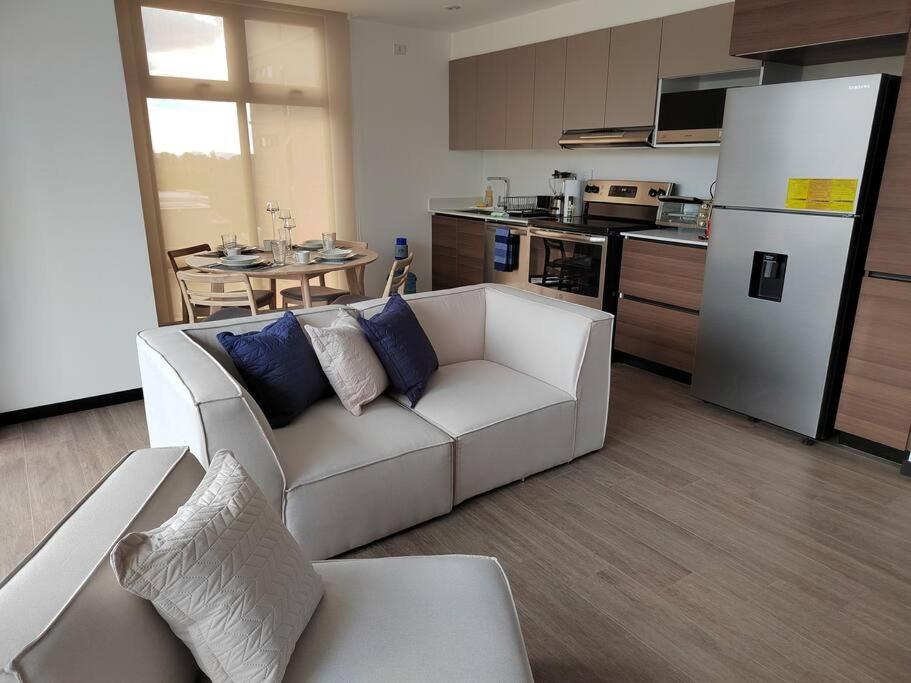 危地马拉Hermoso apartamento nuevo en zona 10!的一间带白色沙发的客厅和一间厨房