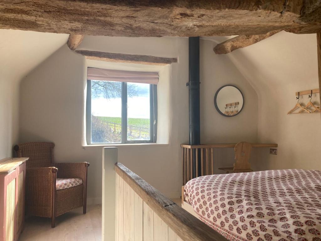 斯托尔河畔希普斯顿Whichford Mill Barn- Soulful retreat.的一间卧室设有一张床、一个窗口和一把椅子