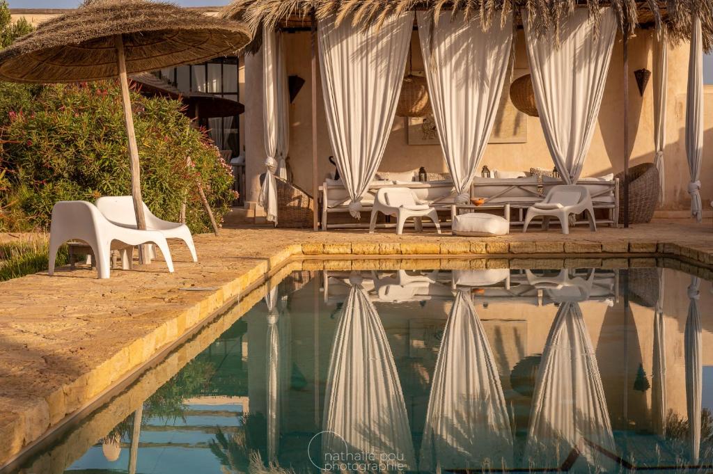 GhazouaDar Alya Essaouira Maison et table d'hôtes的酒店旁的游泳池配有椅子和遮阳伞