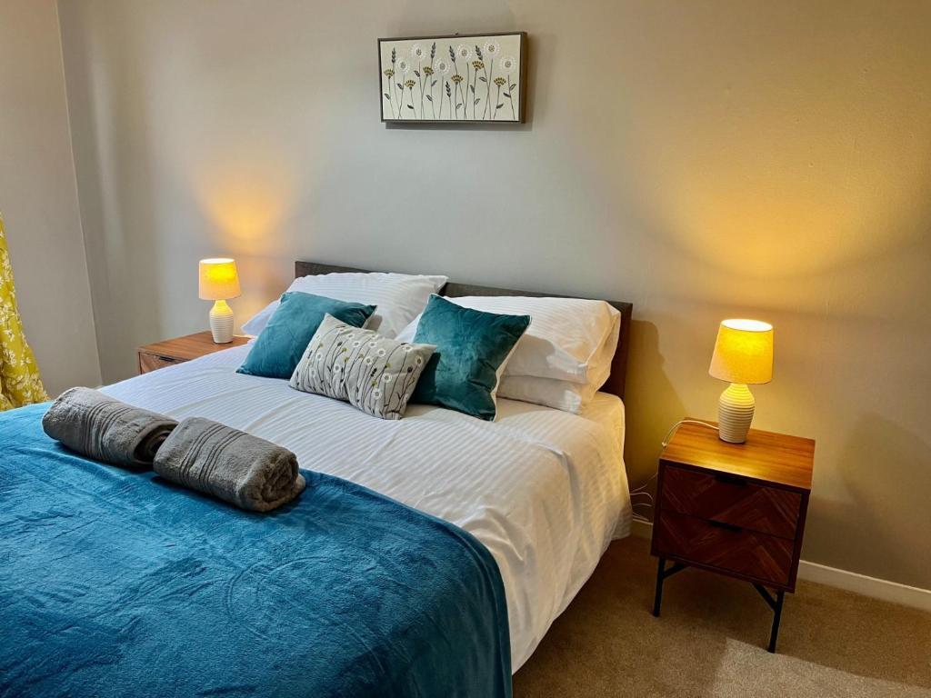 沃灵顿Canada House - Sleeps 6 -3 King or 6 Single Ideal for contractors的一间卧室配有一张带蓝色床单的床和两盏灯。