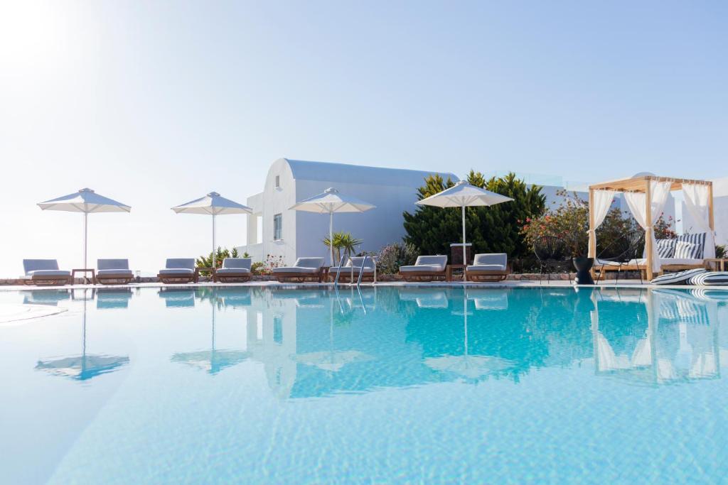费拉天文宫套房酒店的一个带椅子和遮阳伞的大型游泳池