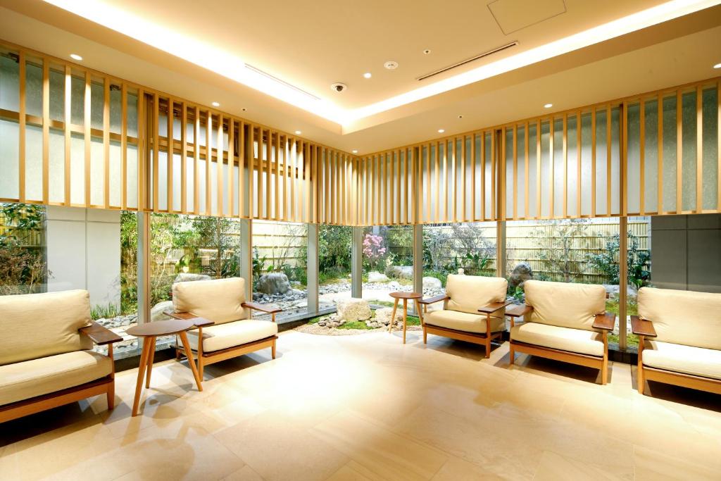 京都Travelodge Kyoto Shijo Kawaramachi的大型客房设有桌椅和窗户。