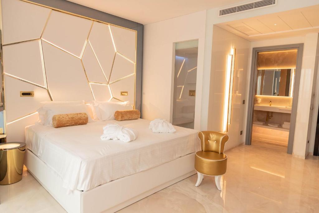 里乔内The Promenade Luxury Wellness Hotel的卧室配有白色的床和金色椅子