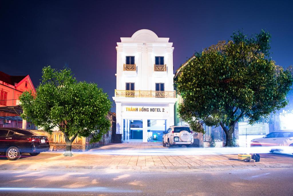 河静THÀNH HỒNG HOTEL的前面有一辆汽车停放的白色建筑