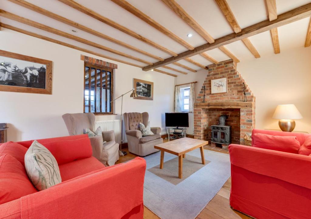 BenendenIden Green Farm Stables的客厅设有2张红色的沙发和壁炉