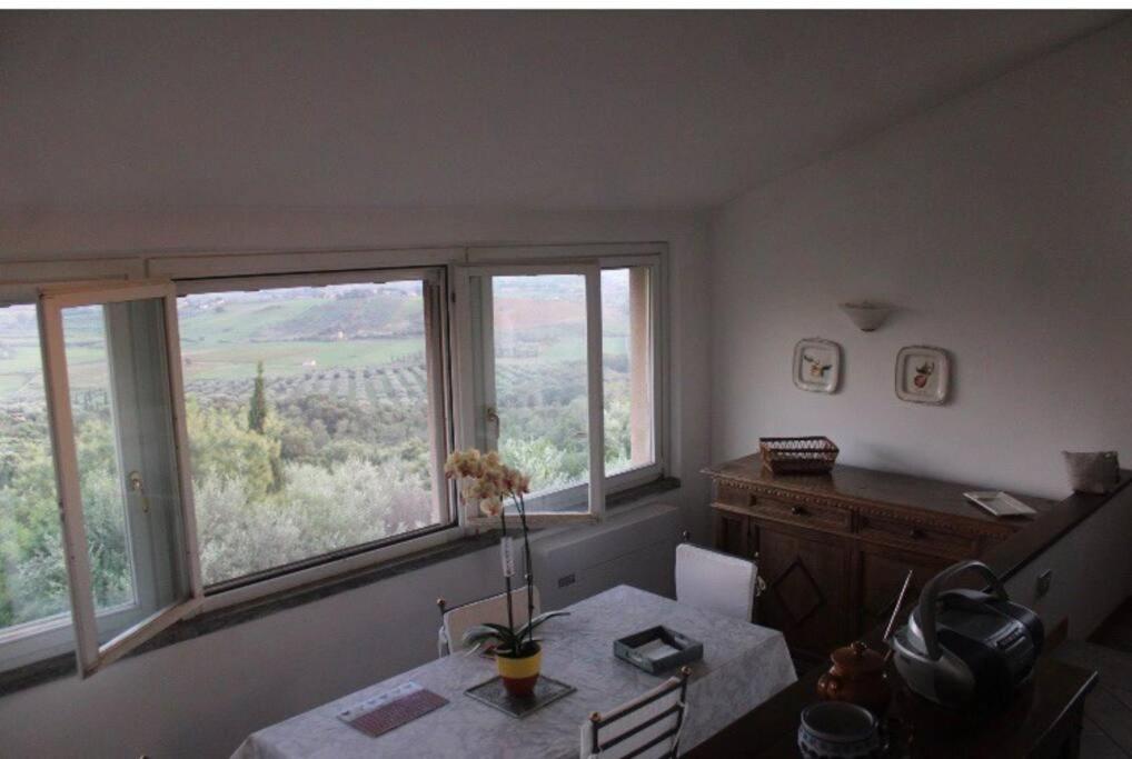 卡帕尔比奥Affittasi a Capalbio per un minimo di 5 notti的一间带桌子和2扇大窗户的用餐室