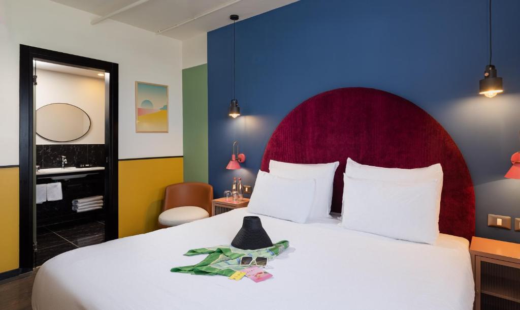 特拉维夫PLAY Seaport Suite Hotel TLV的一间卧室配有一张白色大床和红色床头板