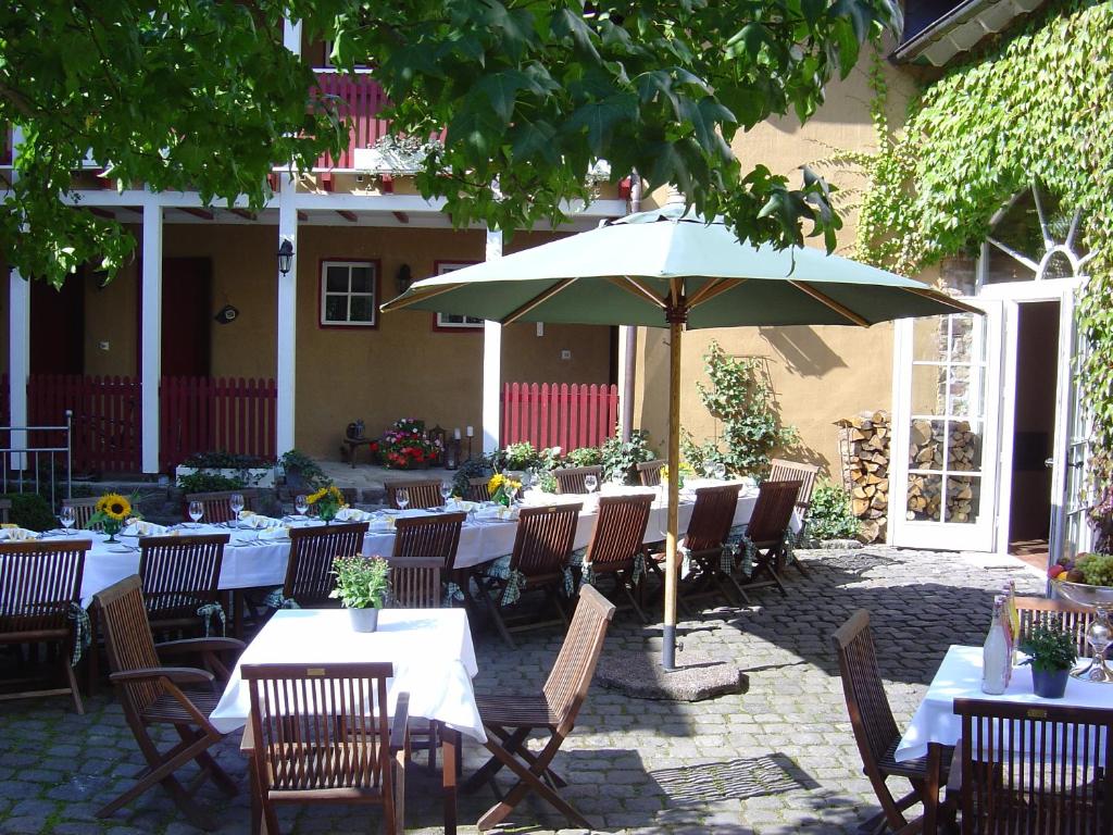 Barweiler阿格内深霍夫酒店的一个带桌椅和遮阳伞的庭院
