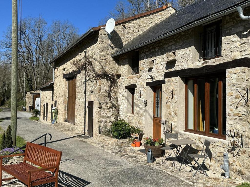 Le Cottage at The Moulin Treillard的石头建筑,前面有长凳