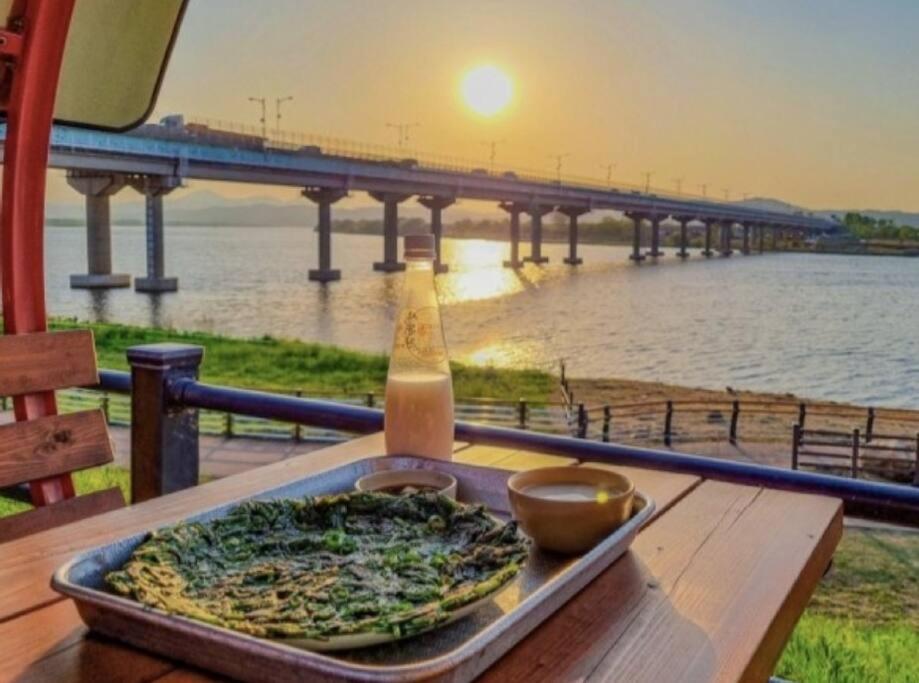 大邱Hosandong House的坐在桌子上的比萨饼,喝着饮料,还享有桥景