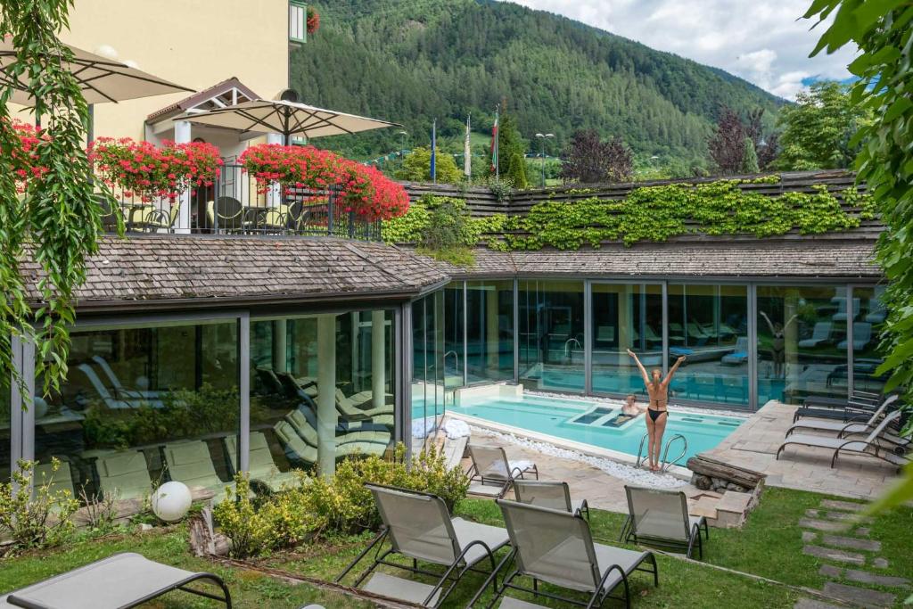 迪马罗Alpholiday Dolomiti Wellness & Family Hotel的庭院内带游泳池和椅子的房子