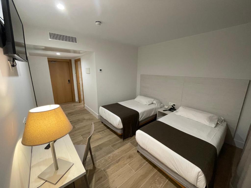桑坦德Eurocity Hotel Santander Centro的小酒店客房设有两张床和一盏灯。
