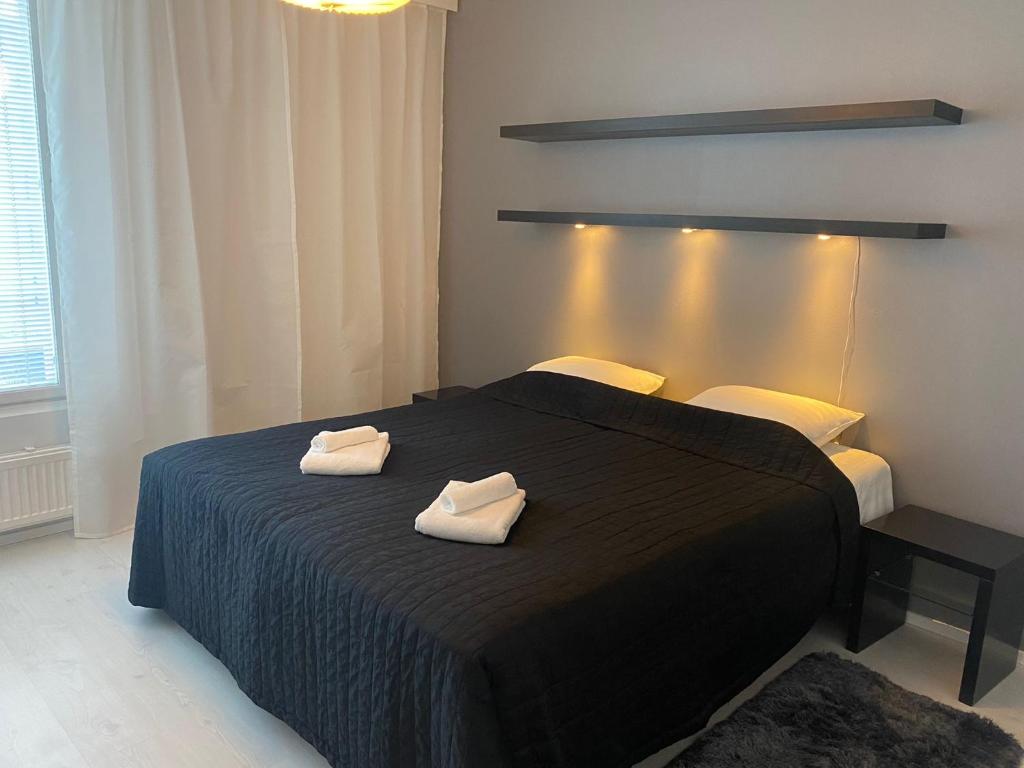 赫尔辛基Gella Serviced Apartments Office的一间卧室配有一张黑色床和两条毛巾
