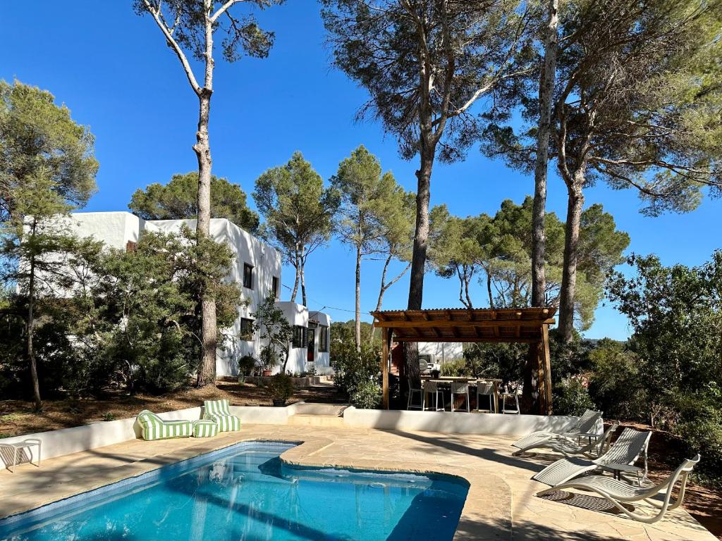 圣塔格鲁迪斯Spacious & Luxury villa in centre Ibiza的一个带椅子和桌子的游泳池以及树木
