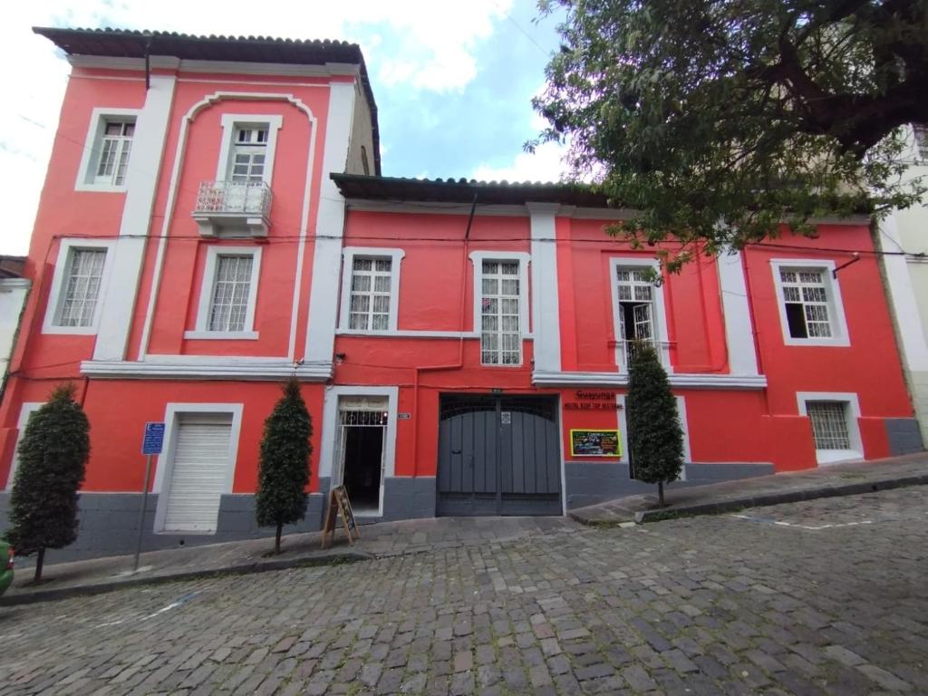 基多Hostal La Guayunga RoofTop的一座红色和白色的建筑,有车道