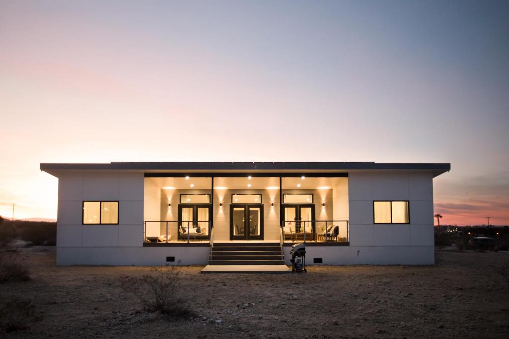 二十九棕榈村Modern Desert Dream - NEW BUILD的一座白色的大房子,背面有日落