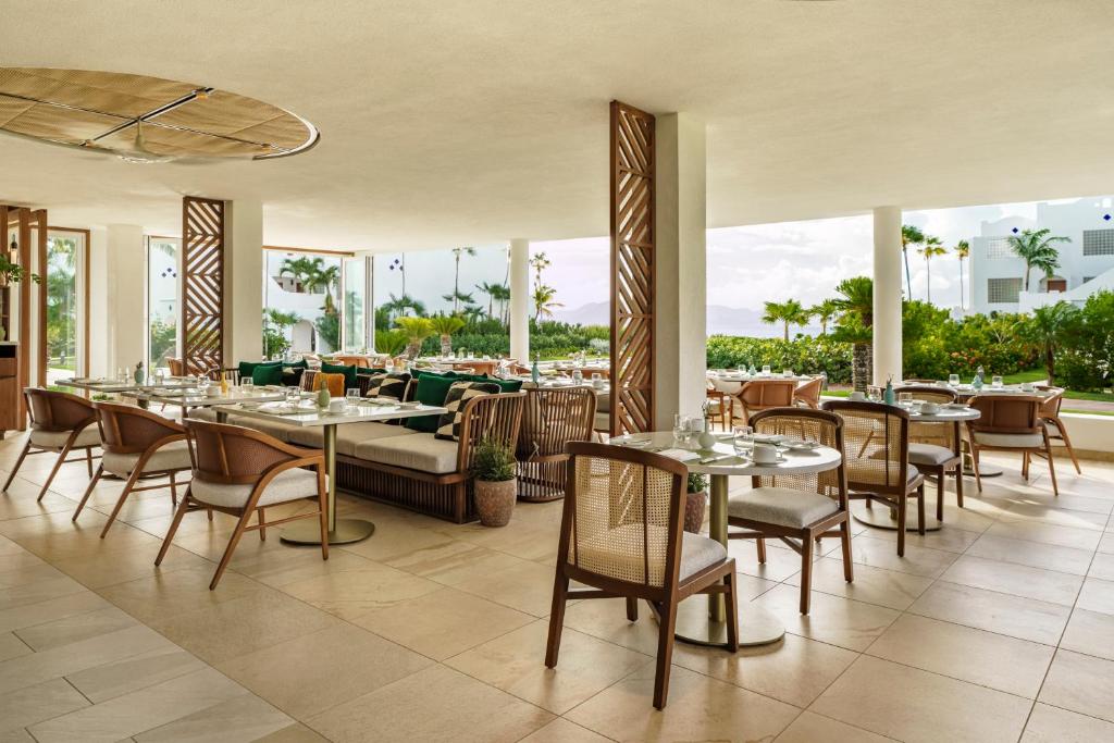 Rendezvous BeachAurora Anguilla Resort & Golf Club的用餐室设有桌椅和窗户。