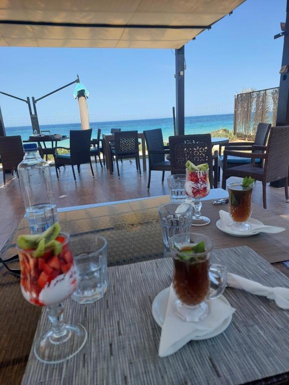 甘达坞伊港Appartement Residence Essayedi Sousse的桌子上摆放着酒杯,还有沙滩