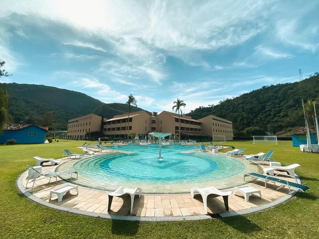 伊泰帕瓦Villa Itaipava Resort & Conventions的一座带椅子的大型游泳池,位于田野中
