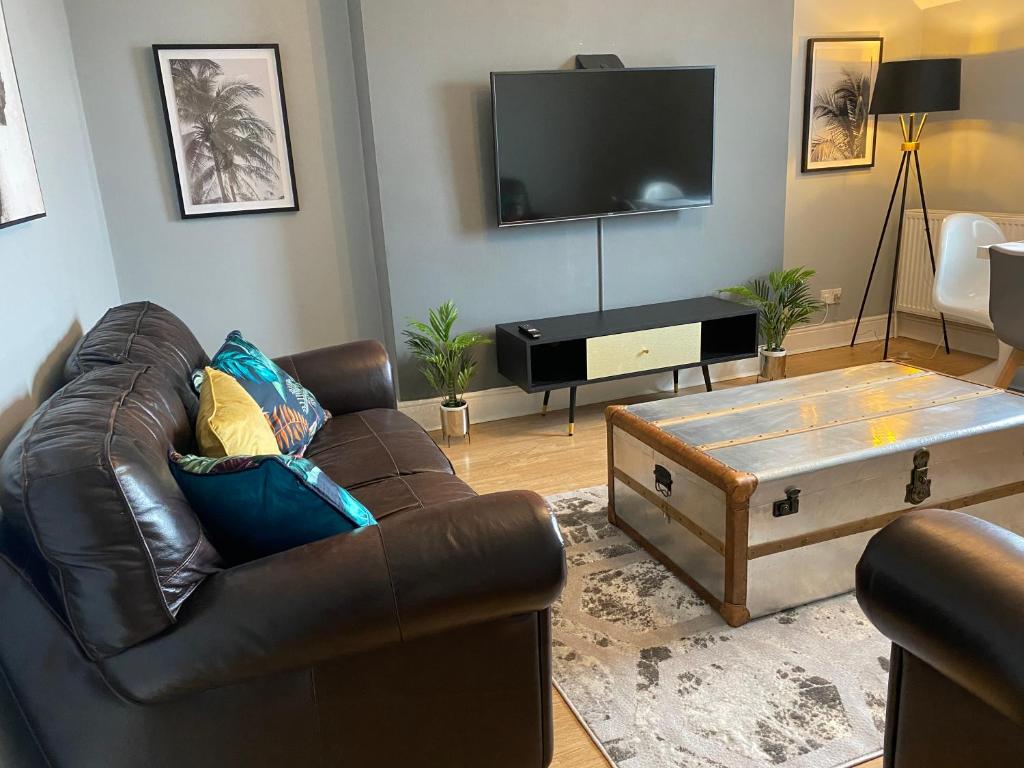 科尔温湾Aspen House - Apartment 3的客厅配有真皮沙发和平面电视