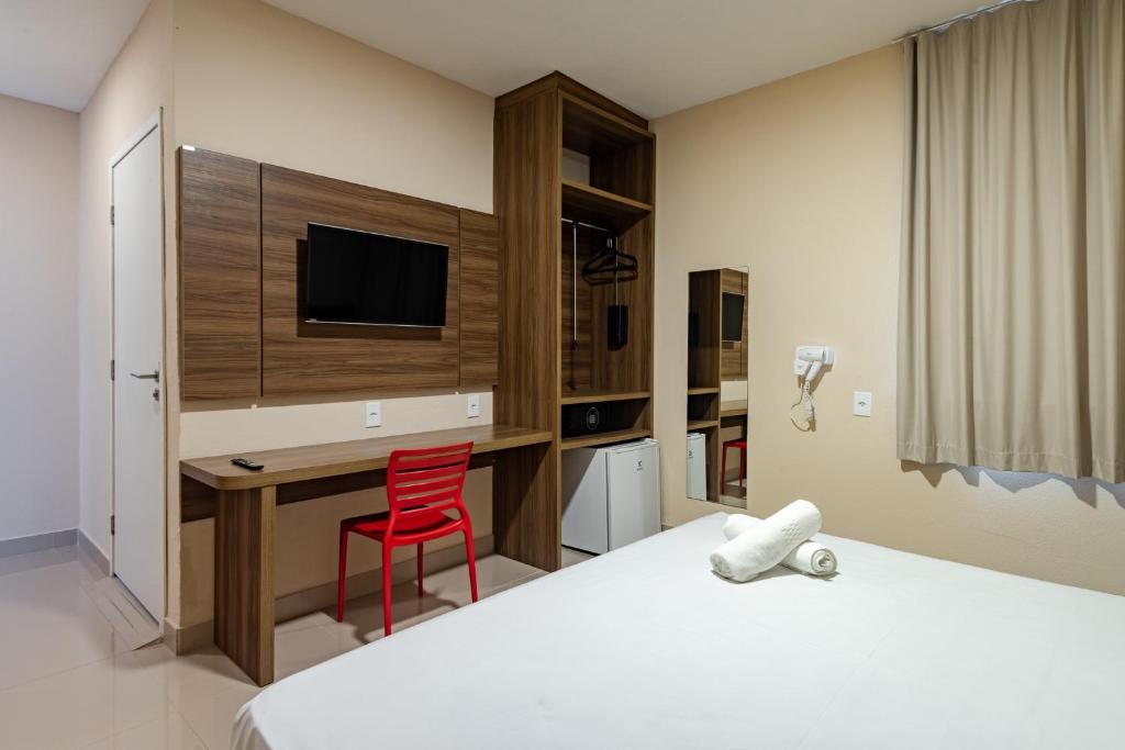 圣路易斯Hotel Santos Dumont Aeroporto SLZ的酒店客房配有书桌和红色椅子