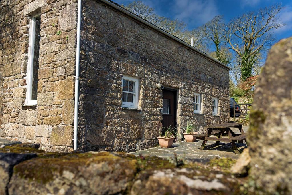 PaulBeautiful Cornish barn in the stunning Lamorna valley with large garden的石头建筑,前面设有野餐桌