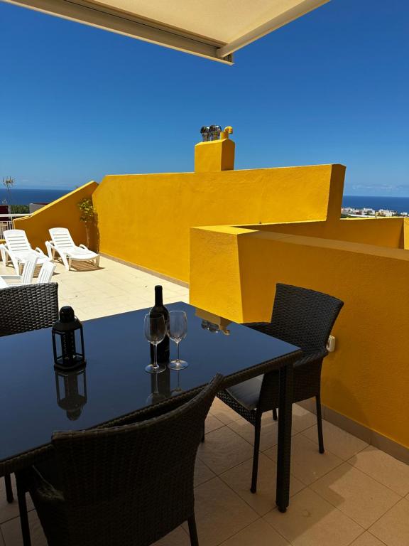 布埃纳维斯塔德尔诺尔特Terraza con vistas mar/montaña的阳台上的桌子上摆放着一瓶葡萄酒和椅子