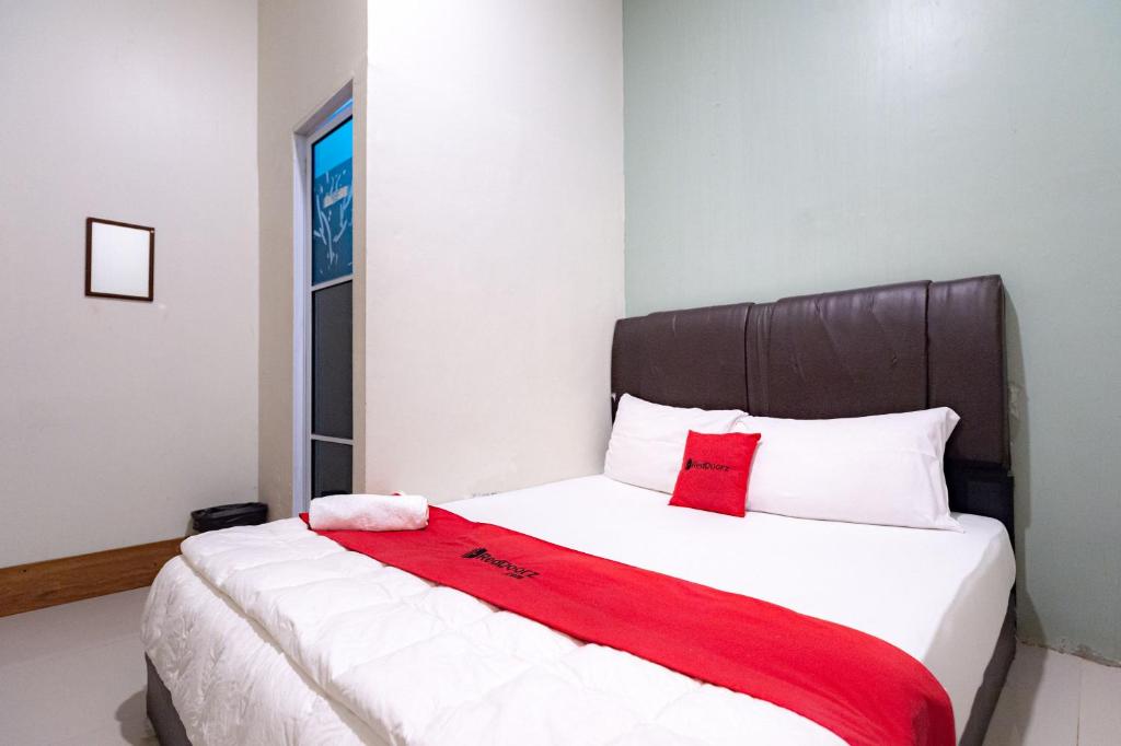 秾莎RedDoorz near Hang Nadim Batam Airport的一间卧室配有一张床铺,床上铺有红色毯子