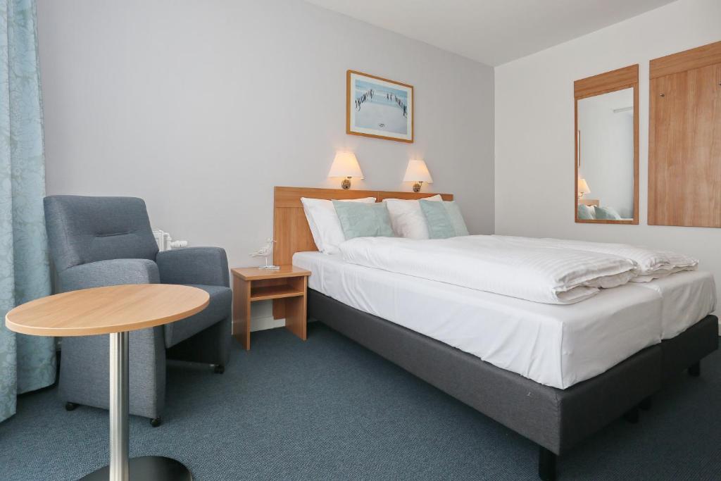 海滨诺德韦克高尔夫兹查特酒店的配有床、椅子和桌子的酒店客房